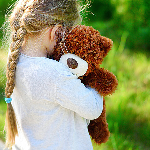 Niña abrazando oso de peluche