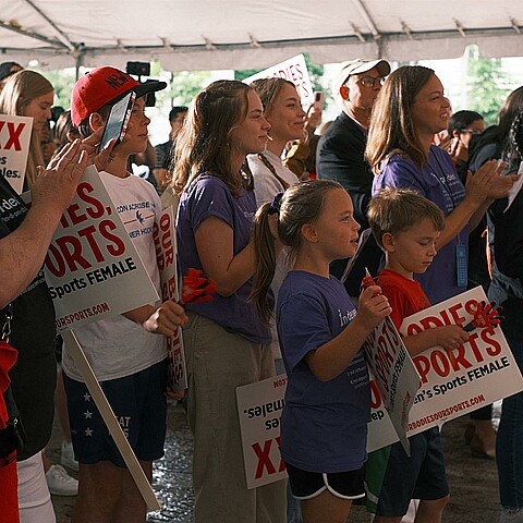 Un grupo de personas sostiene pancartas durante una protesta realizada en contra de la inclusión de atletas trans en deportes femeninos