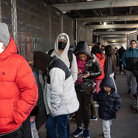 Asylum seekers wait online as Mayor Eric Adams helps distribute donated food and clothing to their families at public school 20 in New York on February 11, 2023