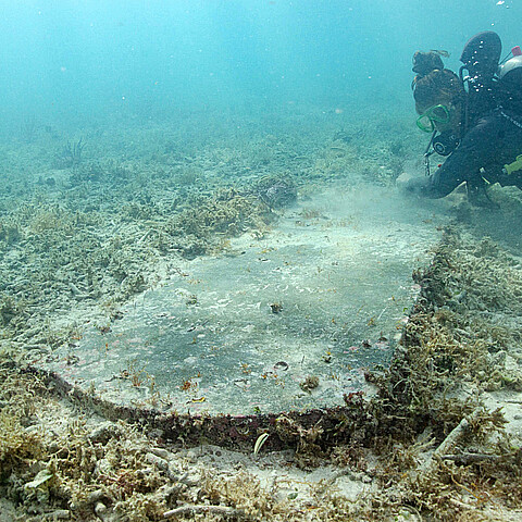 Estudiante graduado de la Universidad de Miami (UM), Devon Fogarty, examina una lápida encontrada bajo el agua por arqueólogos durante un estudio en el Parque Nacional Dry Tortugas 