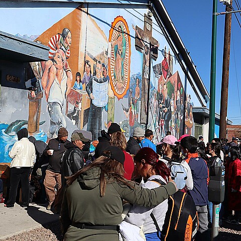 Inmigrantes esperan en una fila para recibir ayuda de alimentos y ropa cerca de un albergue