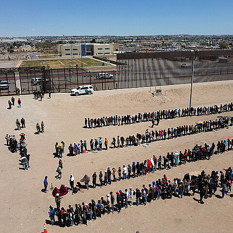 Fotografía de archivo de migrantes formados en la frontera de México y EE. UU.