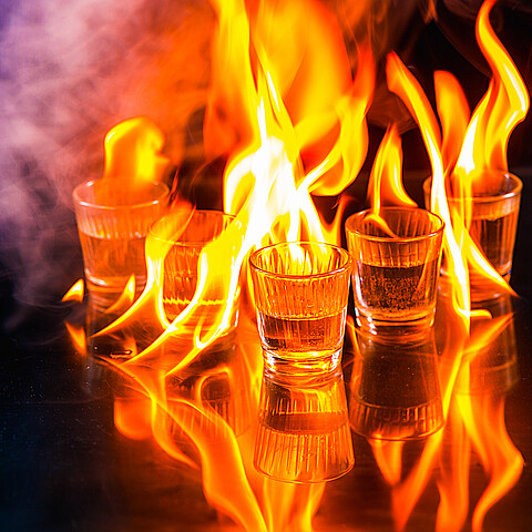Glasses with burning alcohol on black background
