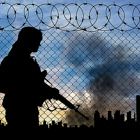 Silouhette of terrorism at border fence