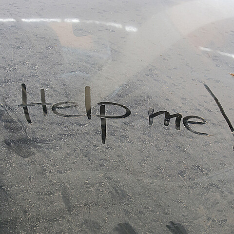 Mensaje de ayúdame escrito en la ventaja de un vehículo