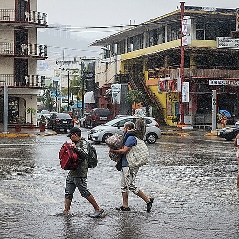 Personas caminan por una calle encharcada debido a las fuertes lluvias en el balneario de Acapulco