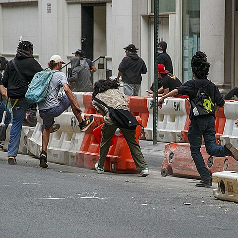 Varias personas derriban a patadas barreras de construcción durante los disturbios que se produjeron después de que un streamer intentara celebrar un sorteo en Nueva York