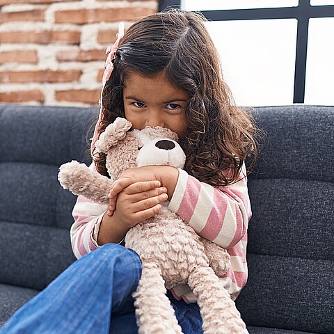 Stock photo of adorable girl kissing and hugging teddy bear