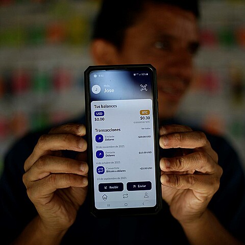Fotografía de archivo en la que se registró a un hombre al sostener un teléfono móvil que muestra una aplicación digital para el uso y canje de criptomonedas a dólares