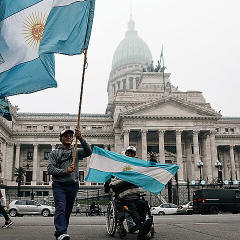 Personas sostienen banderas a las afueras del senado durante un debate
