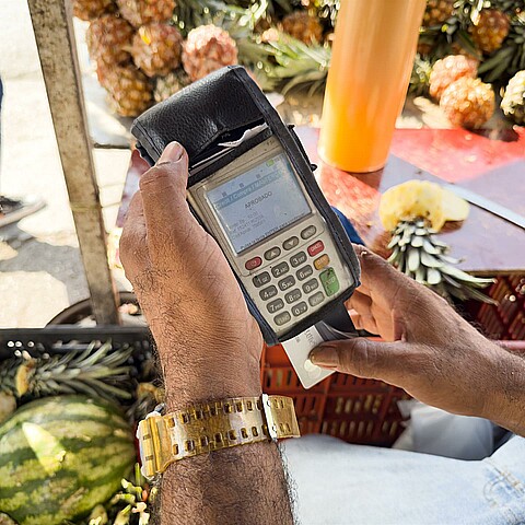 Un hombre hace un cobro con una tarjeta de débito en su negocio