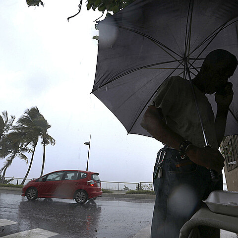 Un hombre camina bajo la lluvia en San Juan (Puerto Rico). Imagen de archivo. 