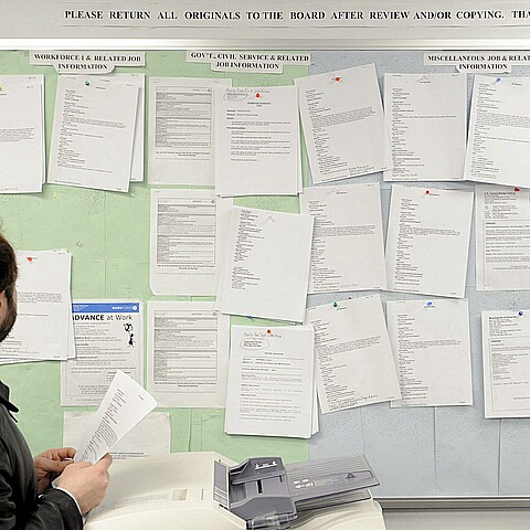 Un hombre busca trabajo en un tablón de anuncios del centro de desempleo