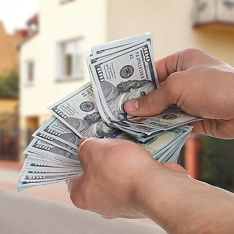 Un fajo de billetedes de 100 dólares en las manos de un hombre