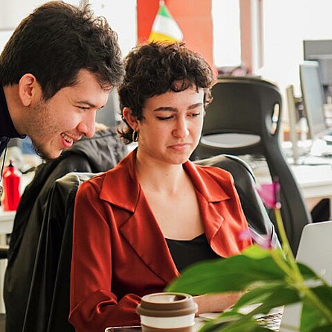 Pareja hablando al frente de un computador en una oficina