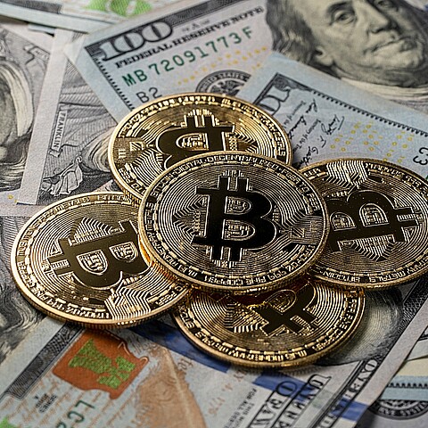 Primer plano de monedas de oro de metal bitcoin criptomoneda en billetes de 100 dólares