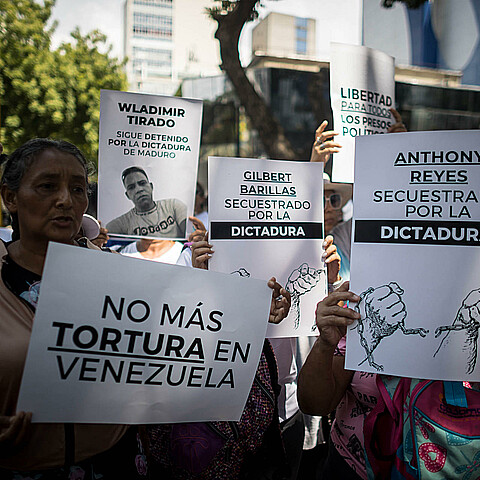 Fotografía de archivo de personas con carteles que muestran imágenes de detenidos durante una manifestación frente a la sede del Ministerio de Servicio Penitenciario, en Caracas. 