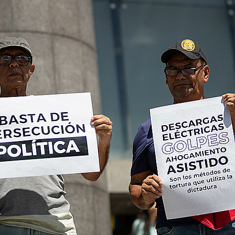 Personas sostienen carteles durante una manifestación frente a la sede de la ONU en Caracas (Venezuela). 
