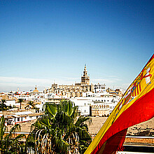 Seville Cathedral with Spain flag flowing in the winds of Sevilla, Spain