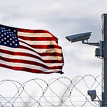 U.S. flag waving in the distance of barbed wire border 