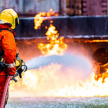 Bombero que utiliza extintor de espuma química para luchar con la llama del fuego del accidente de un camión