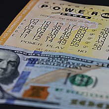 Primer plano de billete de 100 dólares y billete de lotería Powerball