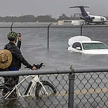 Alguien toma fotos de un auto varado en el agua de la inundación en la carretera West Perimeter del Aeropuerto Internacional de Fort Lauderdale