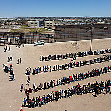 Fotografía de archivo de migrantes formados en la frontera de México y EE. UU.