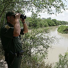A U.S. Customs Border Patrol agent scans an area into Mexico while searching for potential border crossers