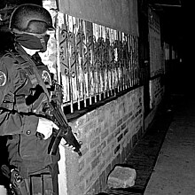 A Special Forces officer guards an alley during a raid against gang members