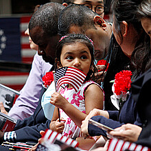 The daughter of an immigrant holds an American flag while she joins her mother's naturalization ceremony on Flag Day at the historic Betsy Ross House in Philadelphia