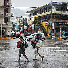 Personas caminan por una calle encharcada debido a las fuertes lluvias en el balneario de Acapulco