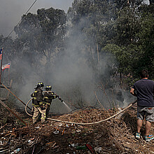 Personas combaten el fuego junto a bomberos en la zona de Las Palmas, durante los incendios forestales que afectan a Viña del Mar
