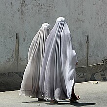 Fotografía de mujeres afganas vestidas con burka que caminan por una carretera en Kandahar, Afganistán. 