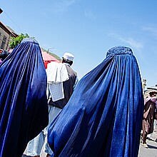 Two women in blue burqas walk on a street in Kabul, Afghanistan