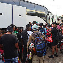 Migrantes hacen fila para abordar uno de los ocho autobuses del 'Corredor emergente de movilidad', en Tapachula (México). 