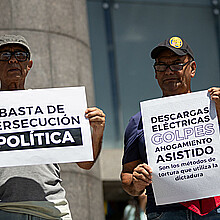 Personas sostienen carteles durante una manifestación frente a la sede de la ONU en Caracas (Venezuela). 