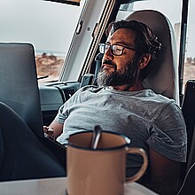 Nómada digital nuevo estilo de vida moderno de trabajo con un hombre adulto atractivo trabajando y relajándose dentro de una camioneta de camper con playa y naturaleza afuera